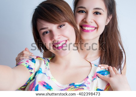 Close up lifestyle selfie portrait of two young positive woman having fun and making selfie, teenage hipster trendy clothes and fresh make up