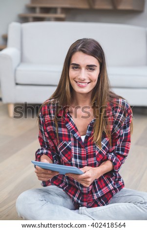 Portrait of beautiful woman using digital tablet in living room at home