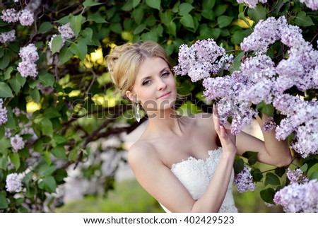 Beauty bride in bridal gown with lace veil on the nature. Beautiful model girl in a white wedding dress. Female portrait in the park. Woman with hairstyle. Cute lady outdoors