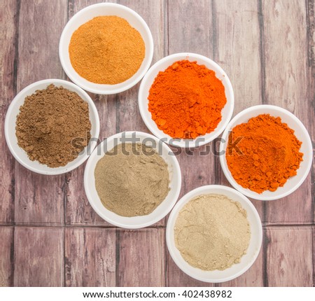 Various hot and spicy spices powder in white bowl over wooden background