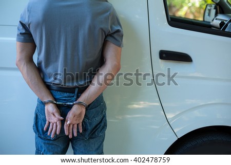 Midsection of prisoner with handcuffs standing against van Royalty-Free Stock Photo #402478759