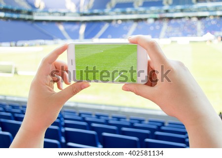 hand the tourist takes a picture with his mobile of the football stadium