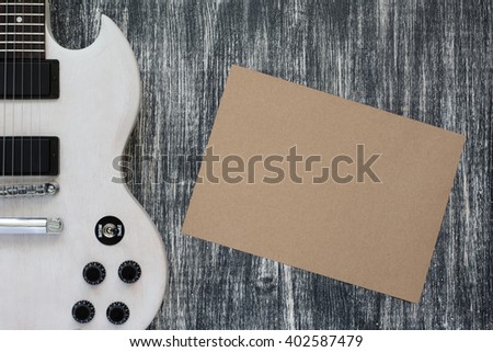 white Electric guitar on wooden grey background, sheet of paper