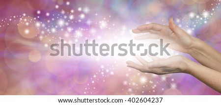 The Magic of Healing - female parallel hands with a burst of white light between and outwardly flowing sparkles on a pink purple background with plenty of copy space Royalty-Free Stock Photo #402604237