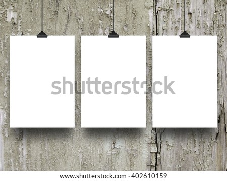 Close-up of three blank frames hanged by clips against grey scratched wooden boards background