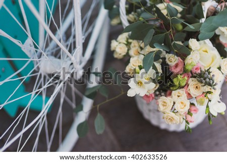 Photo zone for guests at wedding reception. Closeup of white vintage bicycle, turquoise background, flowers and eucalyptus in basket.