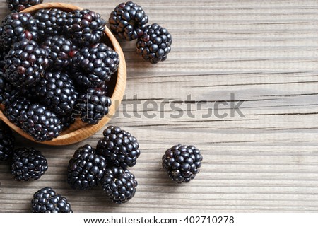 Fresh blackberries in bowl on wooden background. Close up, top view, high resolution product. Harvest Concept