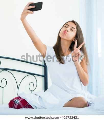 Happy teenage girl smiling in camera and making selfie