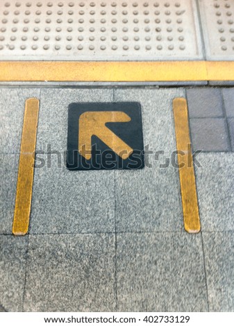 Yellow direction sign on the floor.