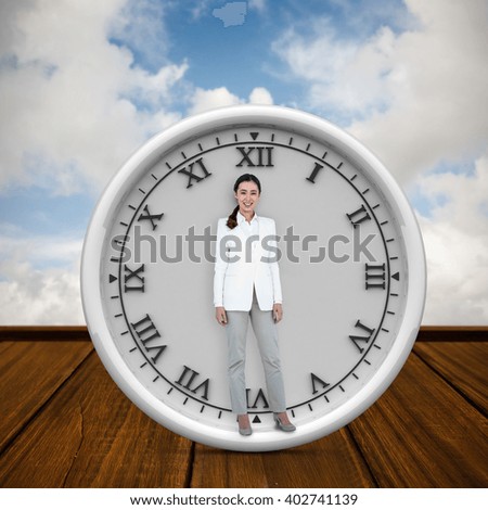 Smiling businesswoman standing straight up against wooden planks against blue sky