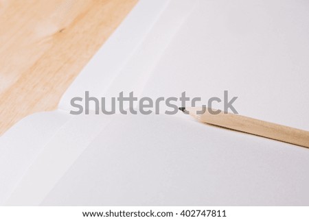 Blank notebook and pencil on wooden table