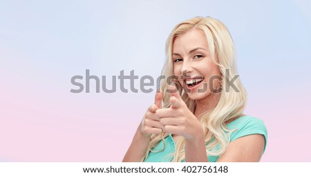 gesture and people concept - happy smiling young woman or teenage girl pointing finger to you over pink background
