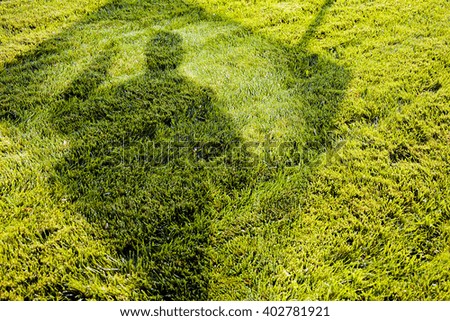 Abstract image of lawn with shadows of man and a billboard
