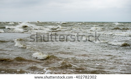 baltic beach in fall with clouds and waves towards deserted dunes. cloudy day