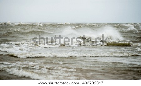 baltic beach in fall with clouds and waves towards deserted dunes. cloudy day