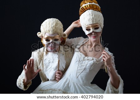 a man and a woman in period costume and wigs and holding a theatrical mask Royalty-Free Stock Photo #402794020