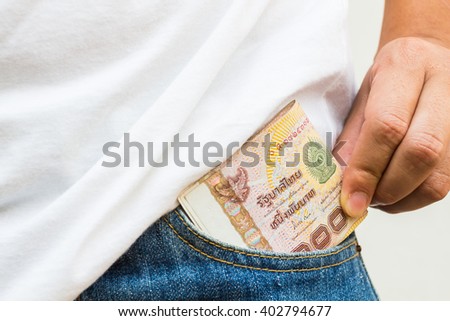 Hand holding Thai money in the jean pocket Royalty-Free Stock Photo #402794677