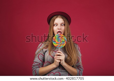 funny girl wearing hat eating big striped lollipop