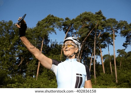 Mature cyclist taking selfie beside forest