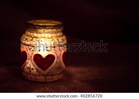 Decorative hand made jar holder for candle. Valentine's Day, Christmas, memorial, romantic, intimate background. Close up candle light in glass.  Royalty-Free Stock Photo #402856720