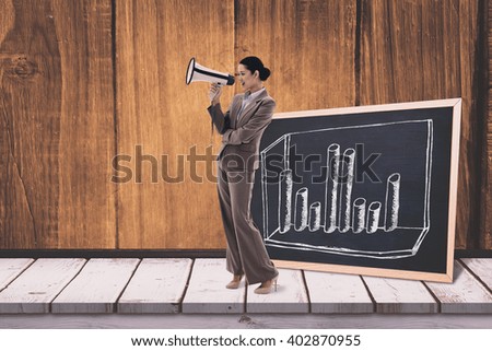 Portrait of a businesswoman shouting through a megaphone against black board on a wooden table