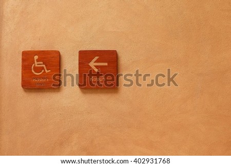 Handicap and toilet wooden signs with cement background