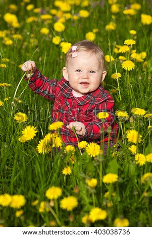 Beautiful happy little baby girl in a wreath  on a  meadow with yellow flowers dandelions on the nature in the park