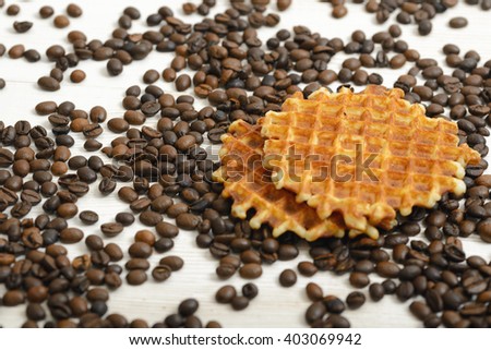 Belgian Waffle biscuit and coffee beans scattered on light surface