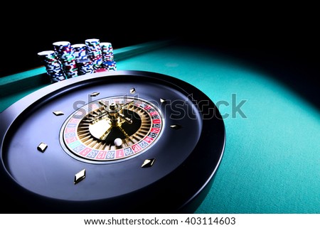 casino theme, high contrast image of casino roulette and playing chips on green canvas