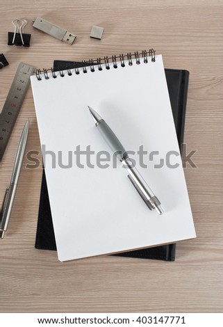 Blank notepad with pen and office supplies on office wooden table