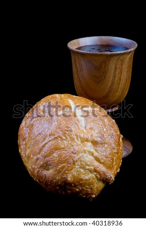 Picturing Christian communion. A  loaf of bread with a cross cut into the top is in front of a wooden chalice filled with wine.