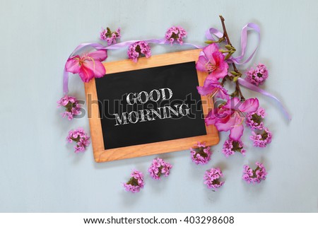 blackboard with the phrase good morning written on it next to fresh flowers

