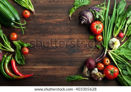 Spring background with fresh juicy vegetables such as radishes, tomatoes, hot peppers, cucumbers and spinach leaves. Vegetarian concept. Place for writing text