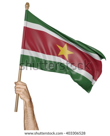 Hand proudly waving the national flag of Suriname