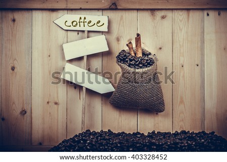 With fresh roasted coffee beans on a pile of wood, sacks of roasted coffee and labels. 