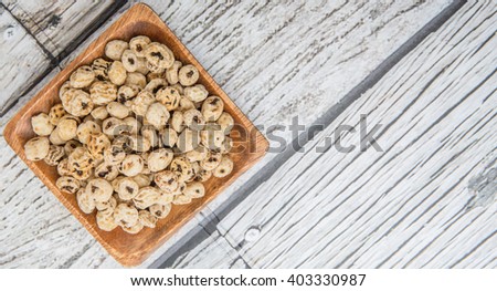 Dried tiger nuts in wooden square bowl over wooden background