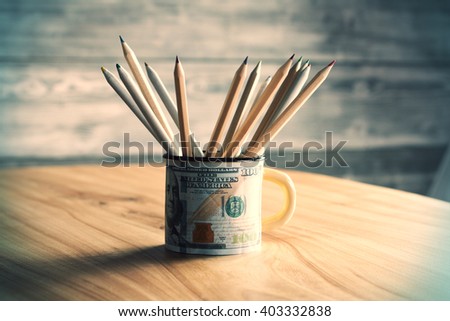 Sideview of dollar print mug with pencils on wooden table