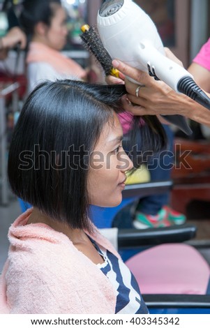 Hairdresser dries the hair customers with hairdryer. Professional hairstyling in a hairdressing salon.