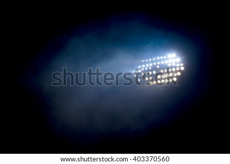 Light tower lit at a stadium during nightime. Royalty-Free Stock Photo #403370560