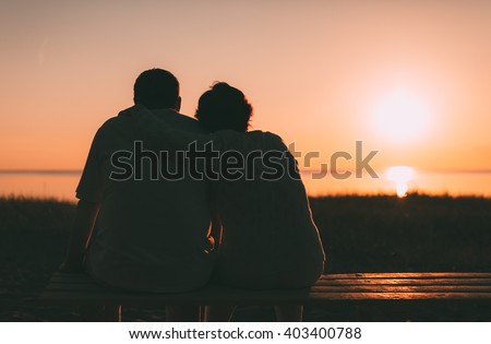 Back view a married couple a silhouette sitting on a bench. Evening photo. Royalty-Free Stock Photo #403400788