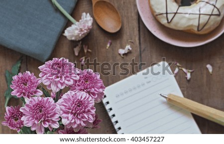 flowers and donut with notebook on wooden background (Natural tone) , top view