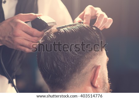 Hairdresser makes hairstyle a man with a beard  Royalty-Free Stock Photo #403514776
