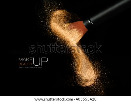 Soft cosmetics brush releasing a cloud of glowing sparkling face powder over a black background with copy space in a beauty and makeup concept Royalty-Free Stock Photo #403555420