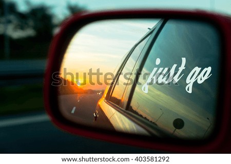 Motivation quote Just go with Sunset reflection in the rear view mirror of a car on a highway