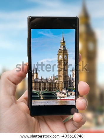 Tourist holds smartphone in hand and photographing Big Ben in London.