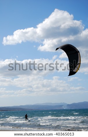 A kitesurfer has the time of his life riding the ocean waves on a sail full of wind