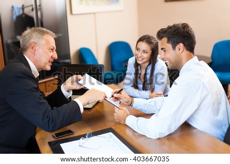 Senior businessman showing a document to sign to a couple