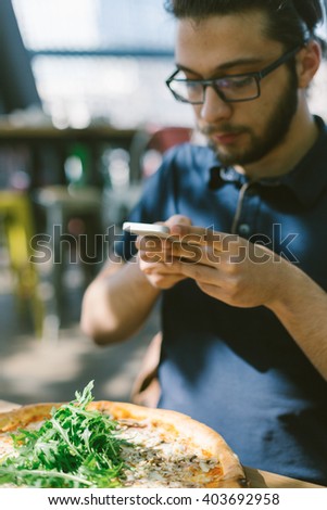 Handsome man taking a picture of his food in a pub