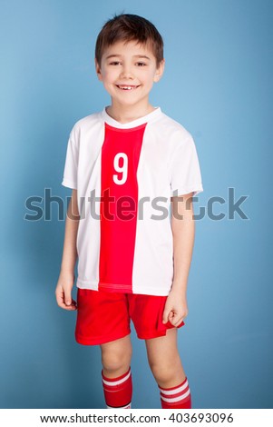 Young soccer player posing on blue background, wearing sportswear