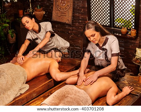 Loving couple  with a soothing ayurvedic spa treatment  in front of a wooden window. Oil massage in  Spa salon. Spa salon decoreted bamboo.